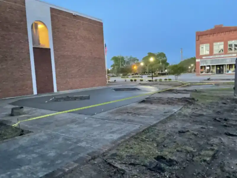 New concrete sidewalk poured in front of commercial storefronts at dusk