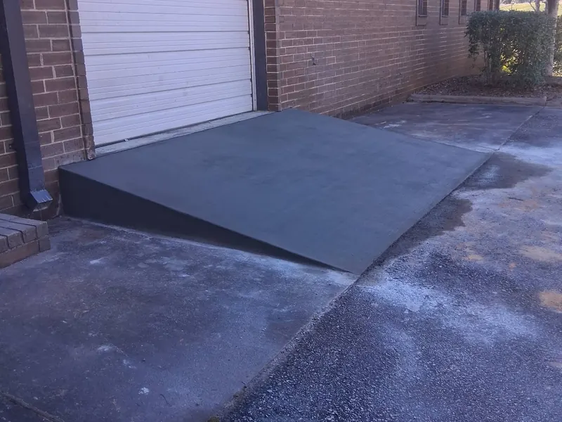 A new poured concrete ramp sloping up to the roll-up loading door