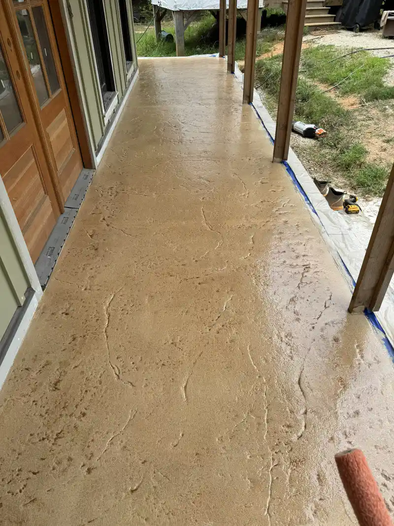 An overlay coating being rolled onto an existing concrete surface, with a paint roller visible in the frame.