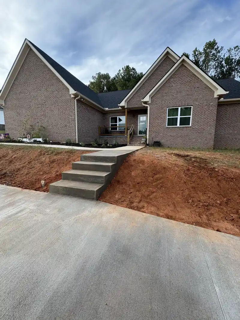 A concrete driveway and front walkway at a two-storey house.