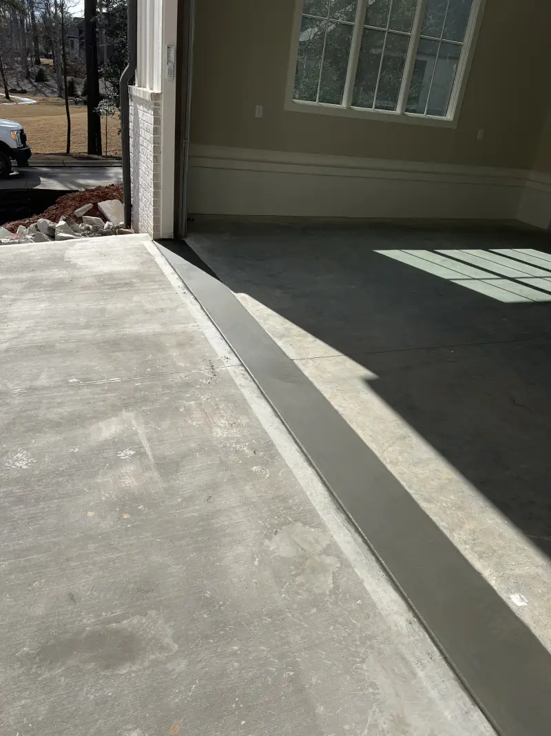 A concrete floor slab inside a finished room with painted walls and baseboards.