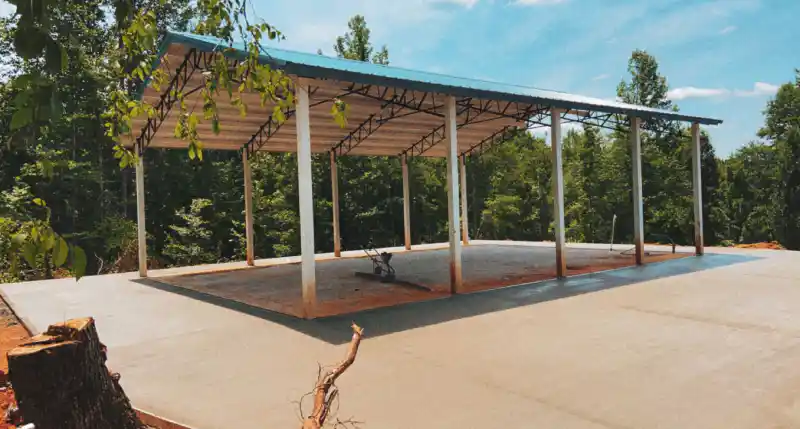 A concrete slab beneath an open-sided pavilion structure.