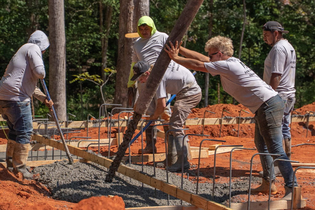 Ace Concrete Construction crew placing concrete from a pump hose into a rebar-reinforced form